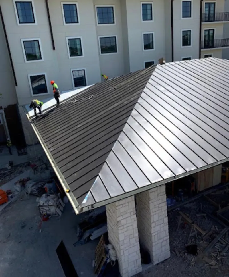 Crew installing standing seam metal roof panels on a commercial project in East Grand Forks